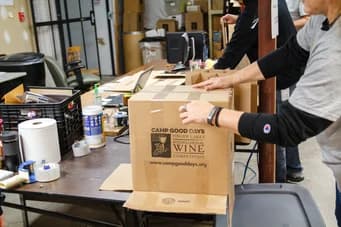 Freiwillige von Qualitrol packen Spendenkisten auf einem Tisch